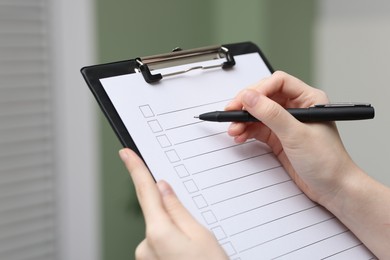 Photo of Woman checking box of paper form indoors, closeup