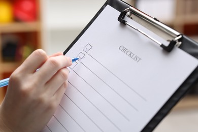 Photo of Woman filling Checklist with pen indoors, closeup