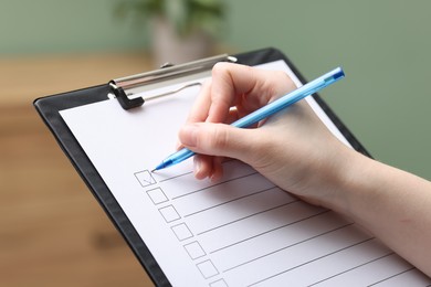 Photo of Woman checking box of paper form indoors, closeup