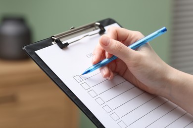 Photo of Woman checking box of paper form indoors, closeup