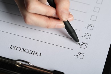 Photo of Woman filling Checklist with pen, above view