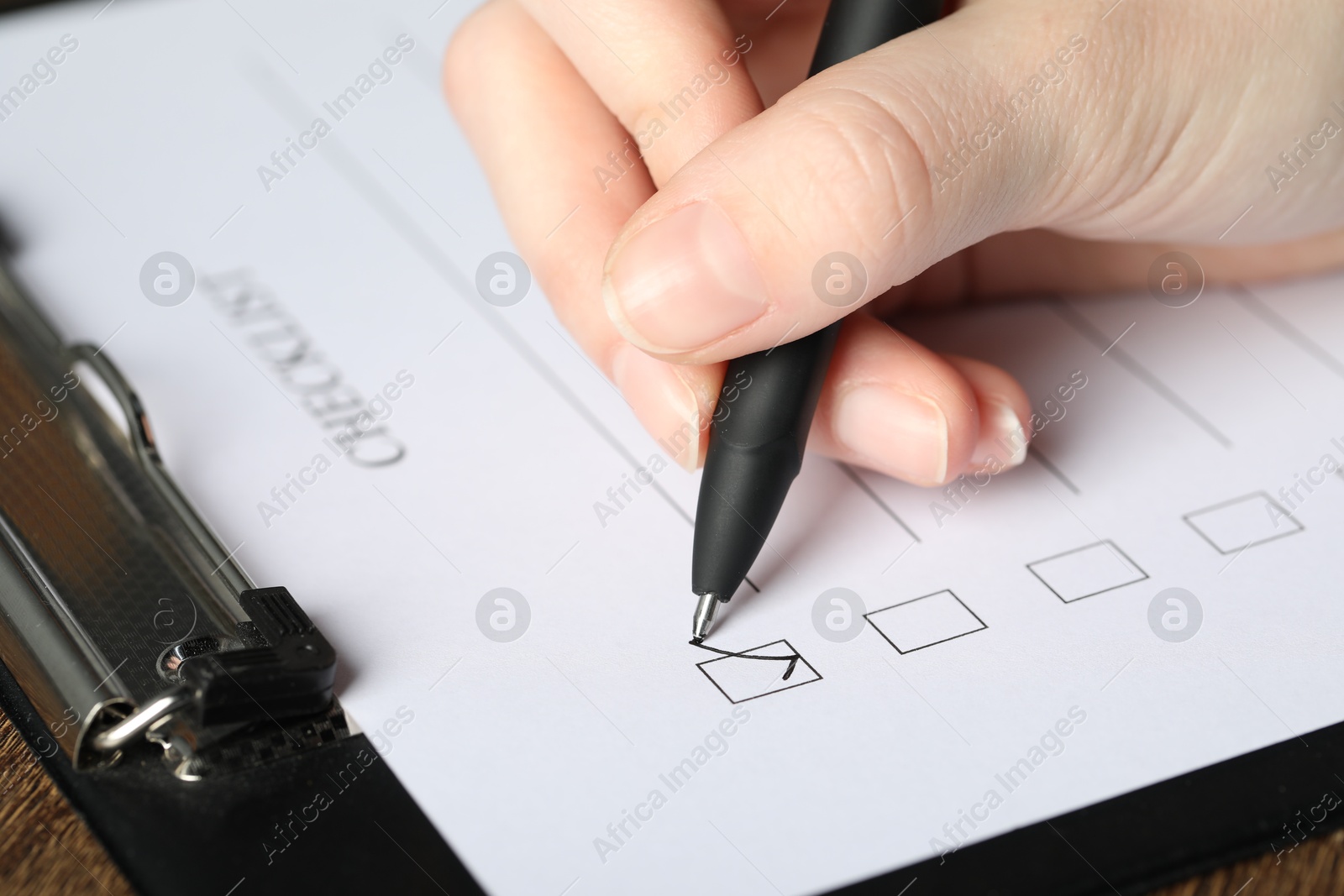 Photo of Woman checking box of Checklist at table, closeup