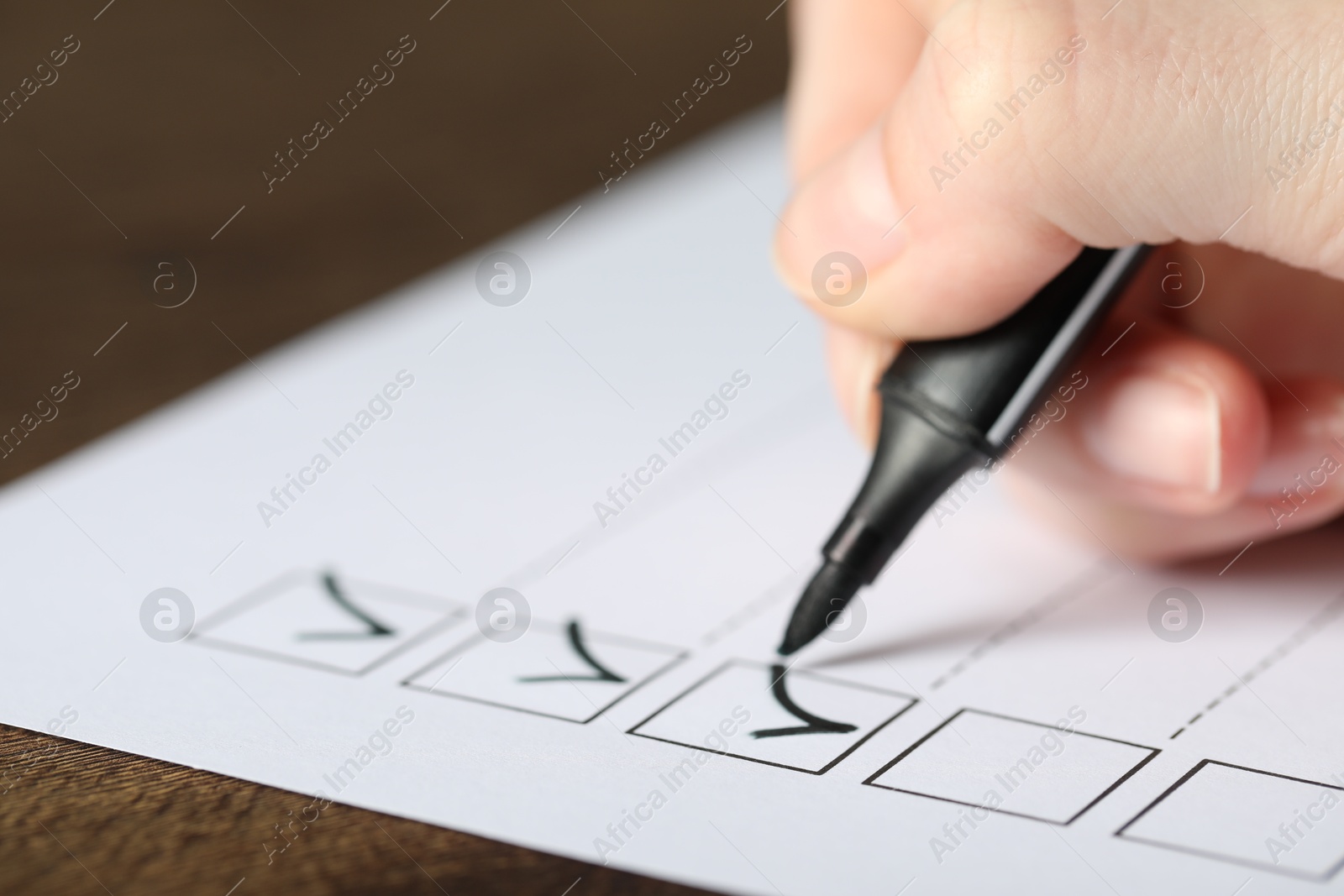 Photo of Woman checking box of paper form at table, closeup