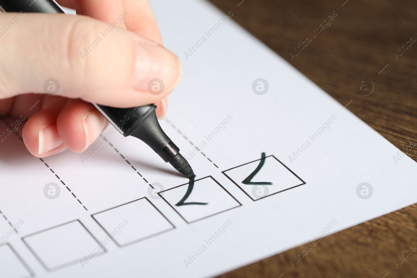 Photo of Woman checking box of paper form at table, closeup