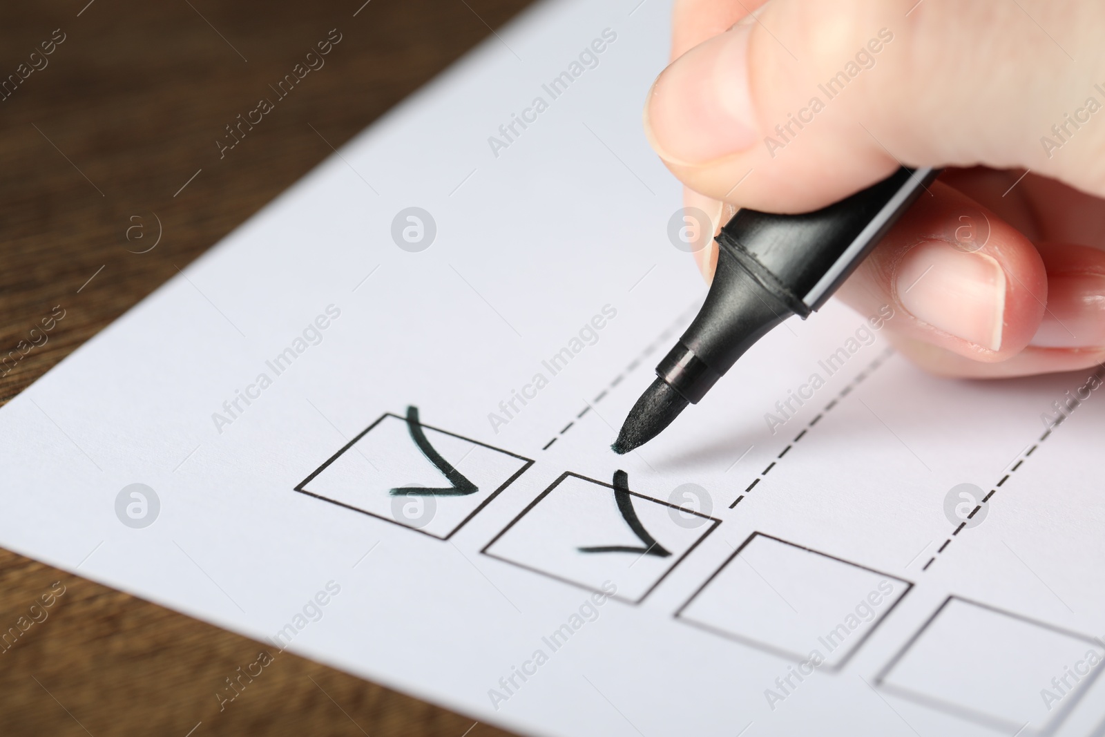 Photo of Woman checking box of paper form at table, closeup