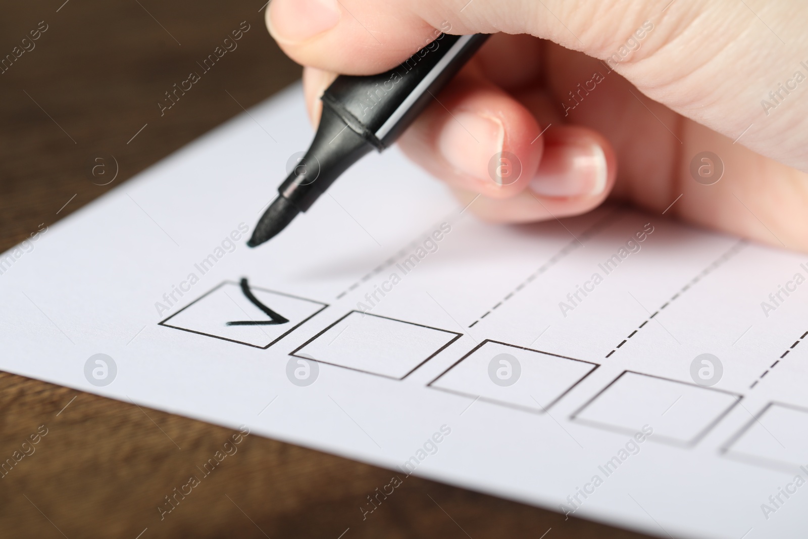 Photo of Woman checking box of paper form at table, closeup