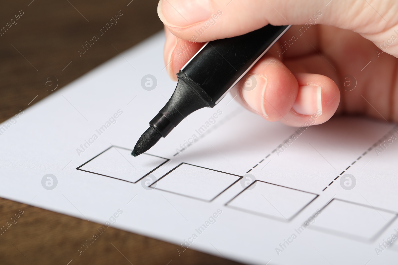 Photo of Woman checking box of paper form at table, closeup