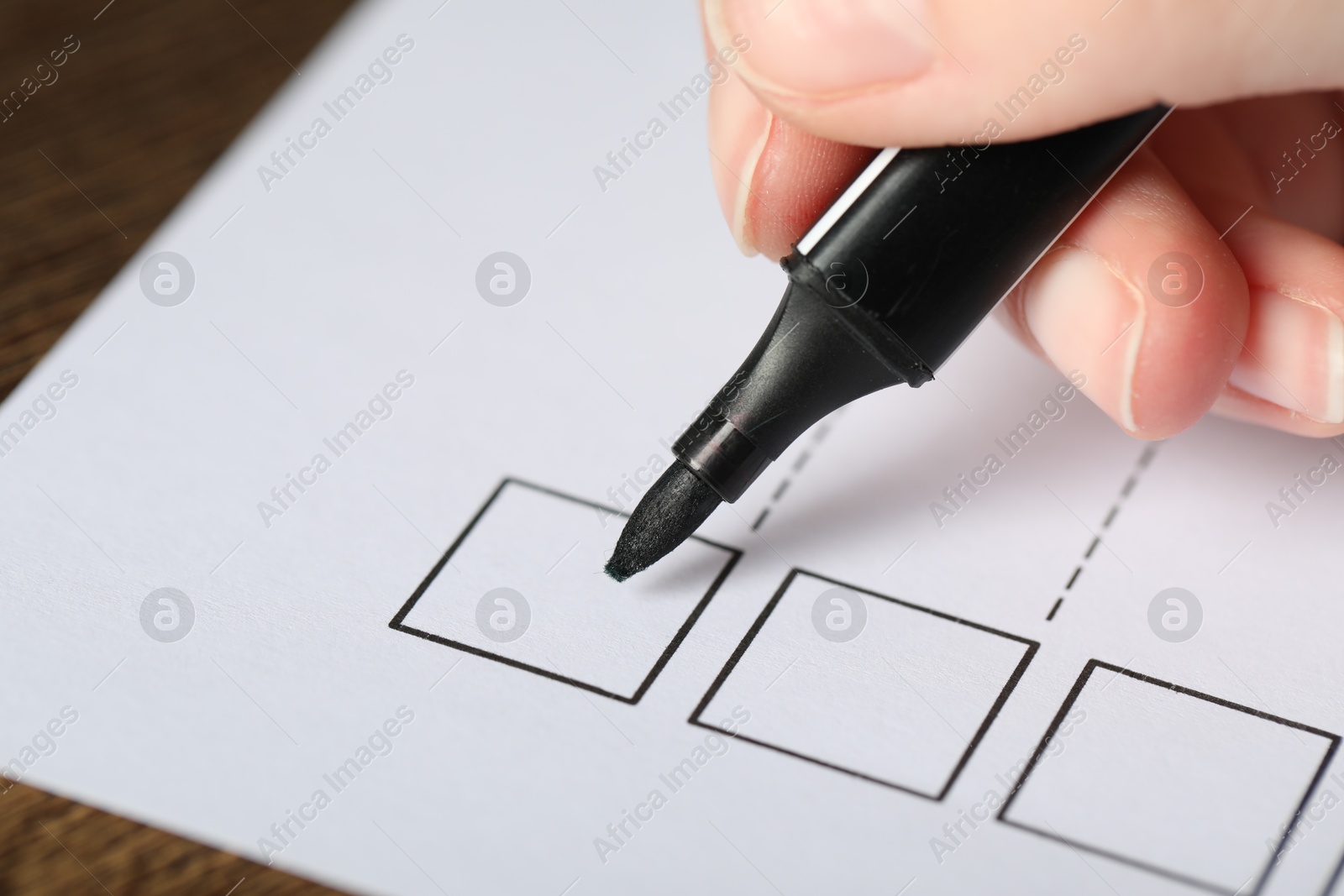 Photo of Woman checking box of paper form at table, closeup