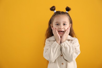 Portrait of cute little girl with missing tooth on orange background, space for text