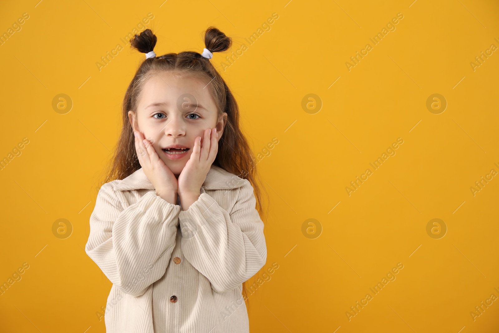 Photo of Portrait of cute little girl with missing tooth on orange background, space for text