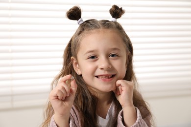 Photo of Cute little girl with missing tooth indoors. Waiting for tooth fairy