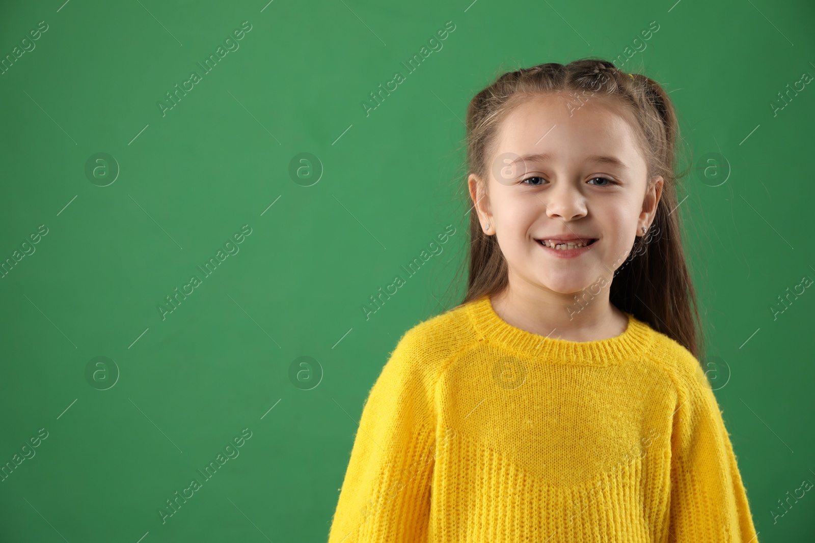 Photo of Portrait of cute little girl with missing tooth on green background, space for text