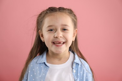 Photo of Portrait of cute little girl with missing tooth on pink background