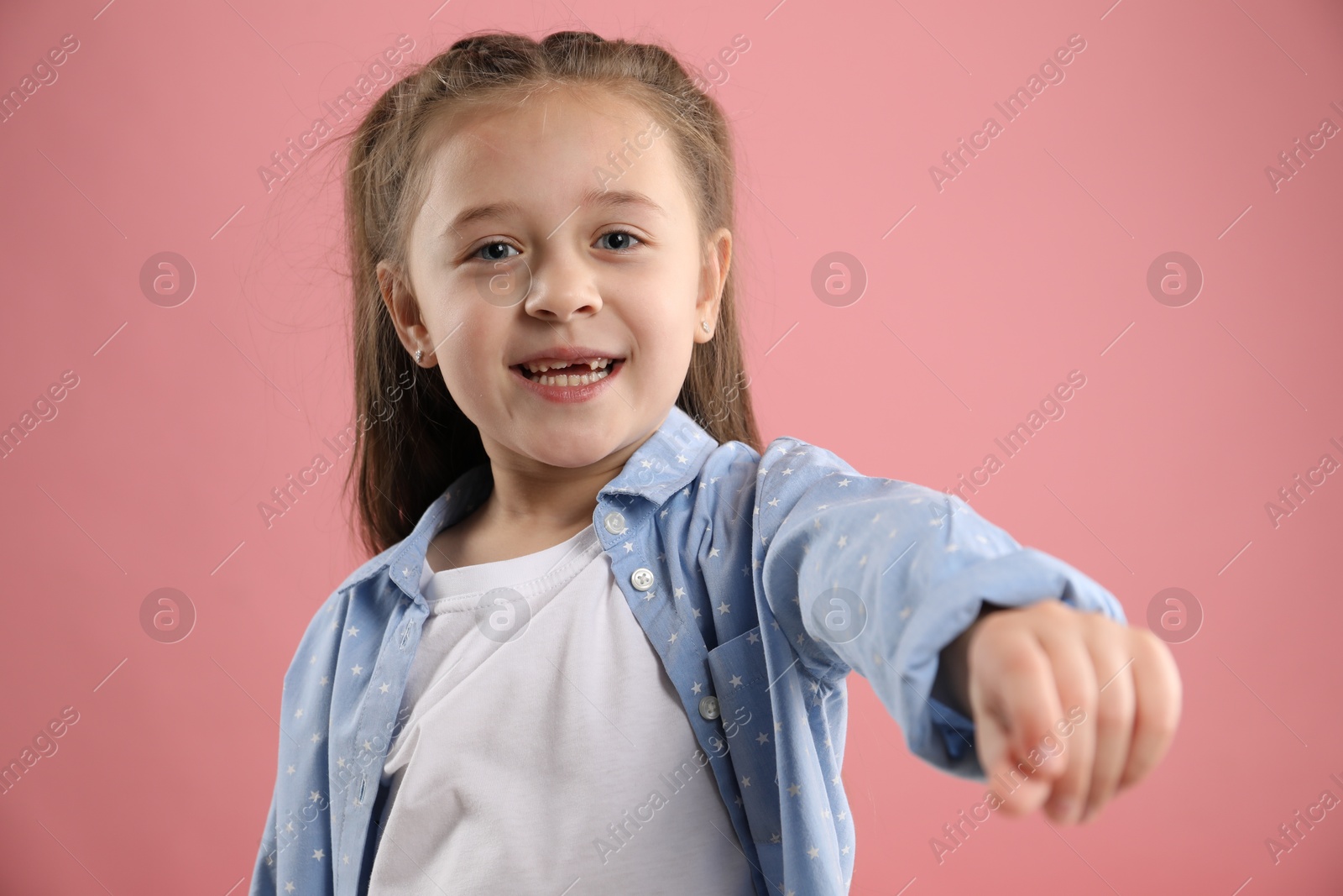 Photo of Portrait of cute little girl with missing tooth on pink background