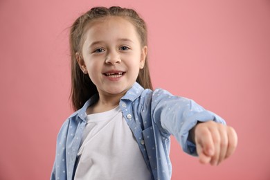 Photo of Portrait of cute little girl with missing tooth on pink background