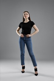 Photo of Beautiful young woman in stylish jeans on grey background