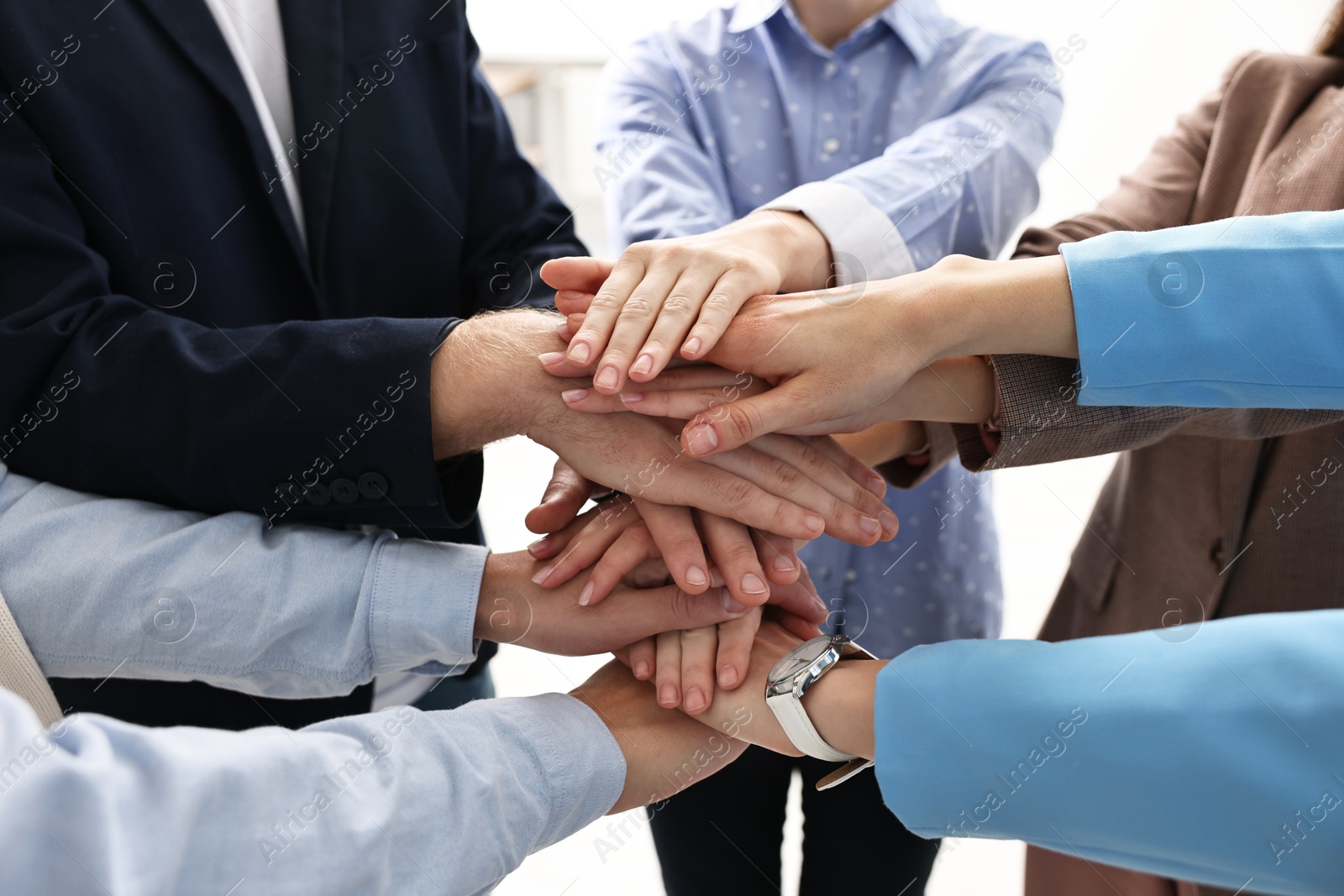 Photo of Teamwork. Group of people joining hands together indoors, closeup