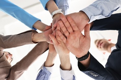 Photo of Teamwork. Group of people joining hands together indoors, bottom view