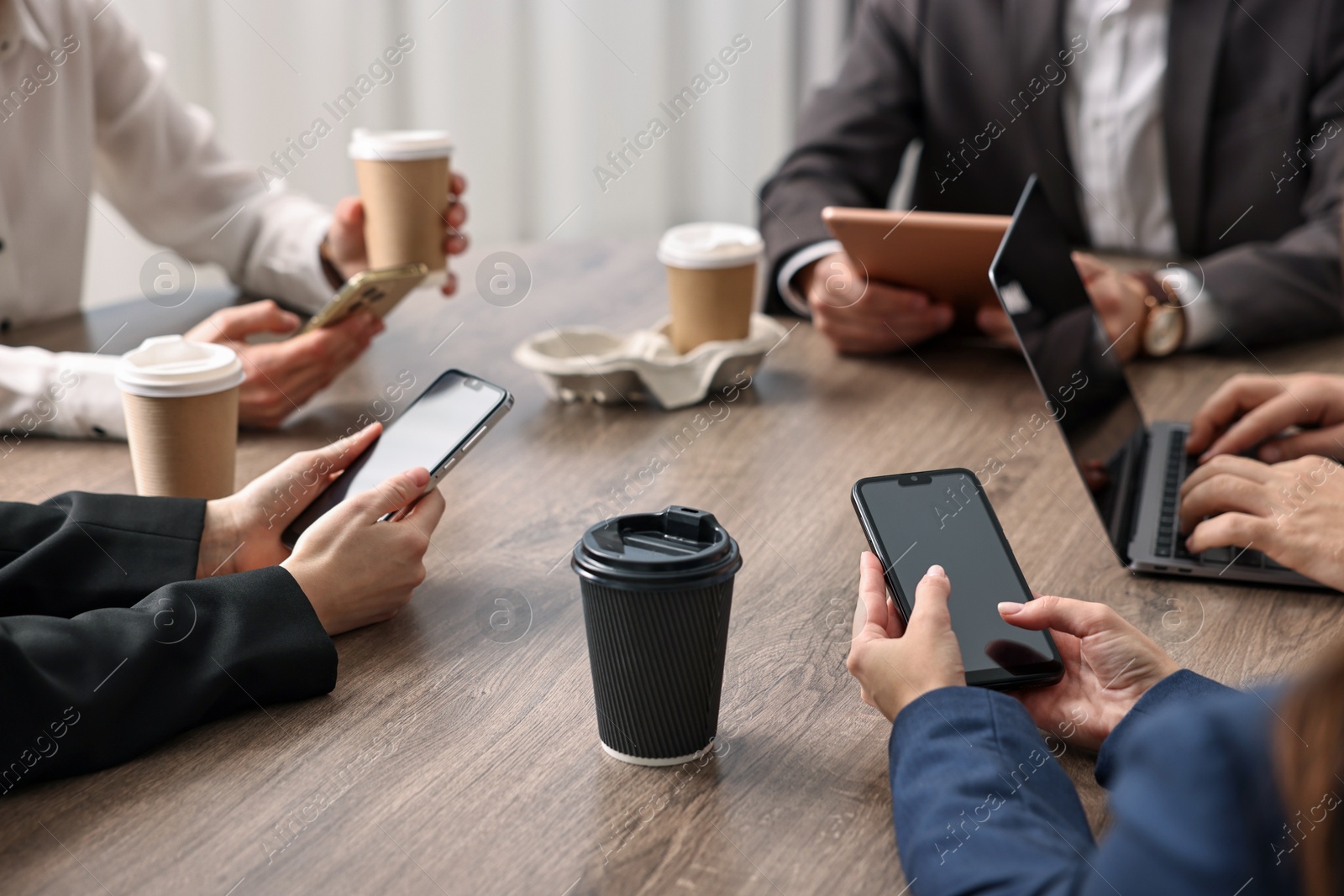 Photo of Group of people using different gadgets at wooden table in office, closeup. Modern technology