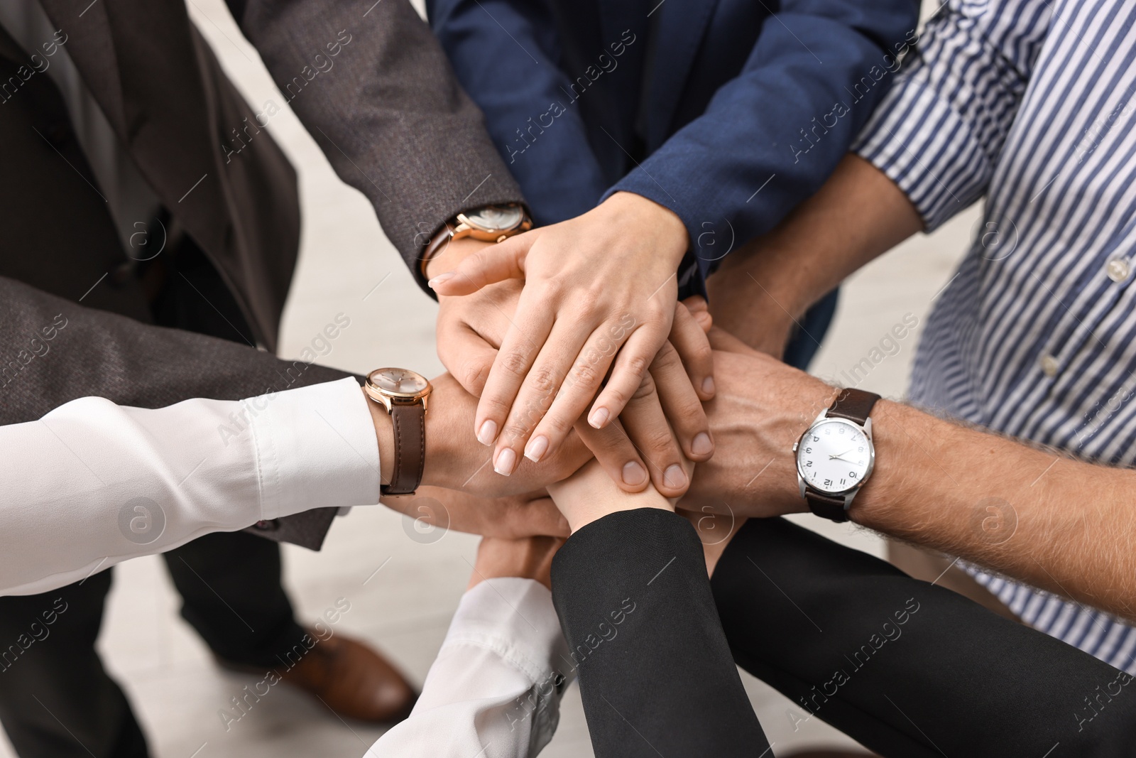 Photo of Teamwork. Group of people joining hands together indoors, above view