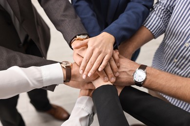 Teamwork. Group of people joining hands together indoors, above view