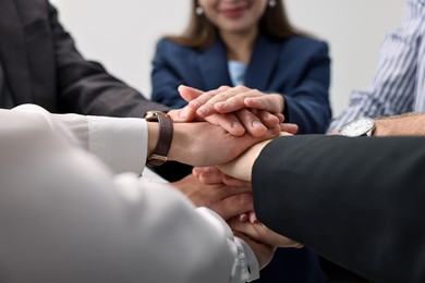 Photo of Teamwork. Group of people joining hands together indoors, closeup