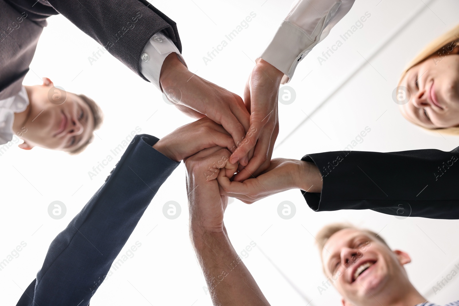 Photo of Teamwork. Group of people joining hands together indoors, bottom view