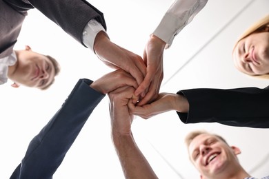 Teamwork. Group of people joining hands together indoors, bottom view