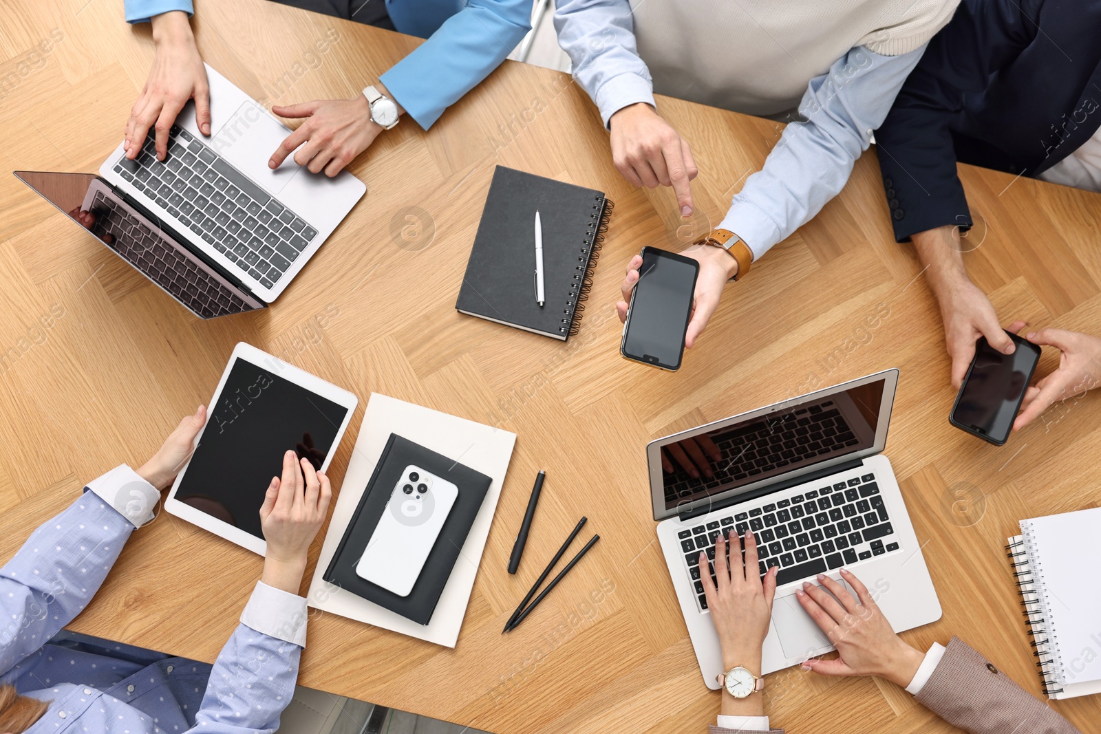 Photo of Group of people using different gadgets at wooden table in office, top view. Modern technology