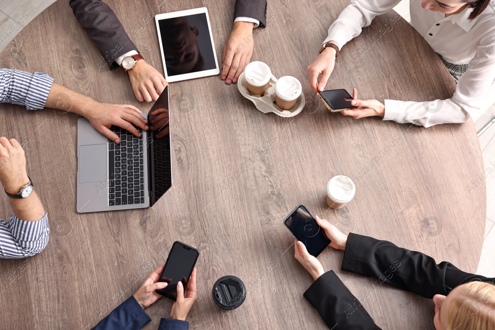 Photo of Group of people using different gadgets at wooden table in office, top view. Modern technology