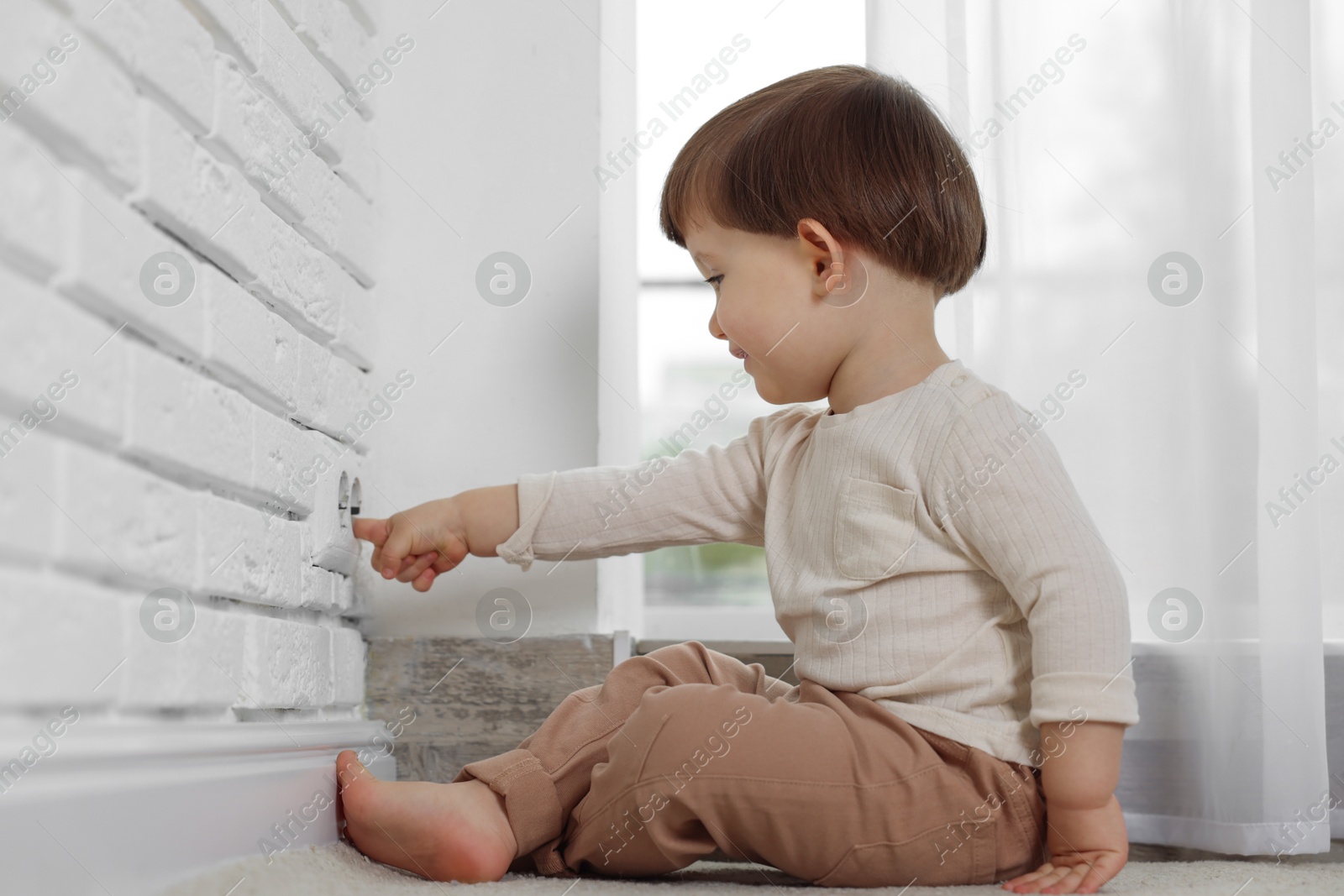 Photo of Little boy playing with electrical socket at home. Child in danger