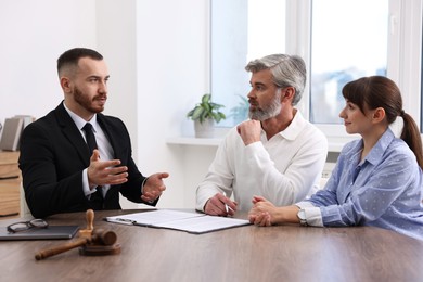 Couple having meeting with professional notary at wooden desk indoors