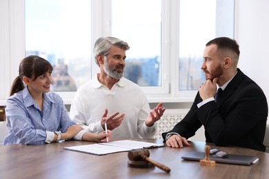 Couple having meeting with professional notary at wooden desk indoors