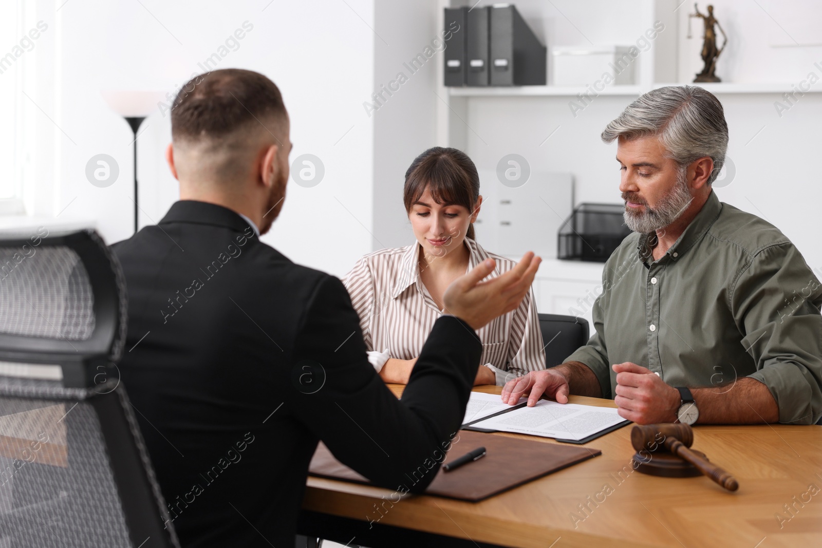 Photo of Couple having meeting with professional lawyer at wooden desk indoors