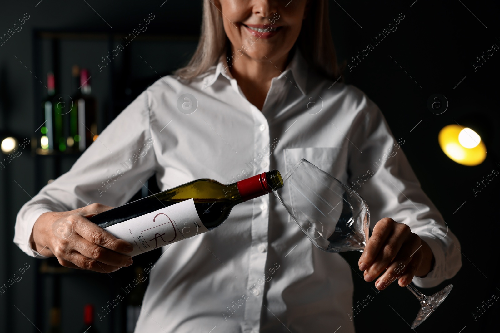 Photo of Professional sommelier pouring red wine into glass indoors, closeup