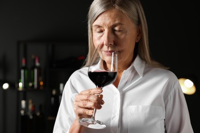 Photo of Professional sommelier tasting red wine in glass indoors