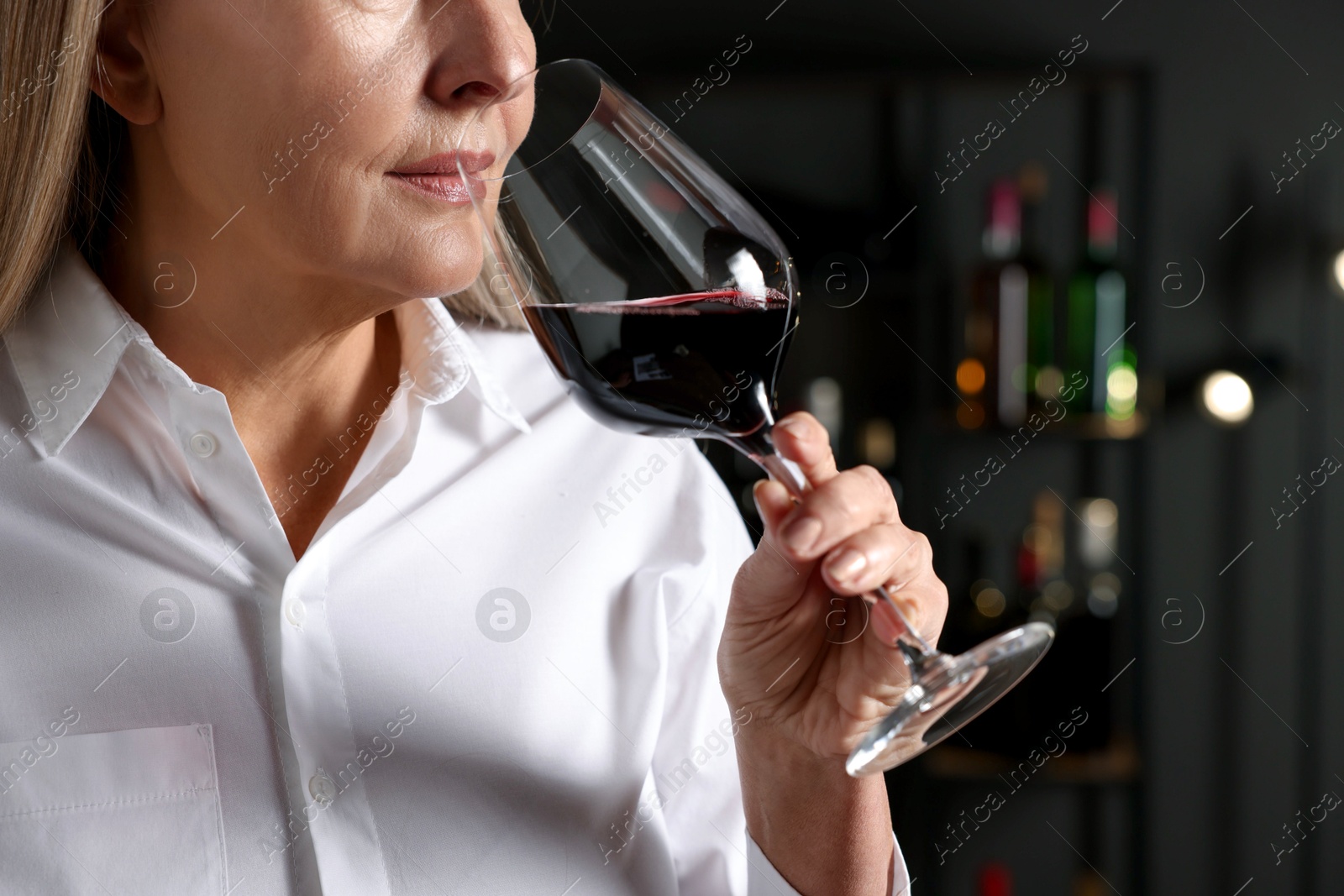 Photo of Professional sommelier tasting red wine indoors, closeup