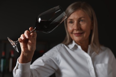 Photo of Professional sommelier analyzing quality of red wine indoors, selective focus