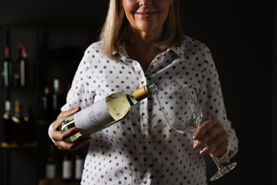 Photo of Professional sommelier pouring white wine into glass indoors, closeup