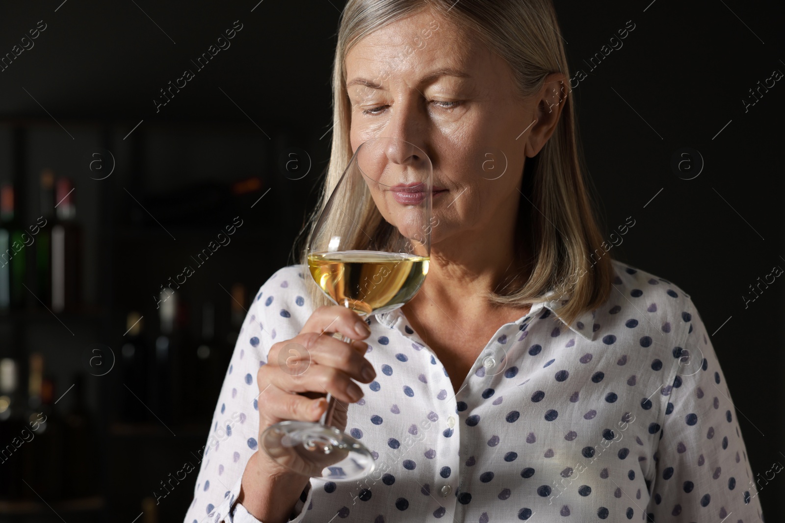 Photo of Professional sommelier tasting white wine in glass indoors