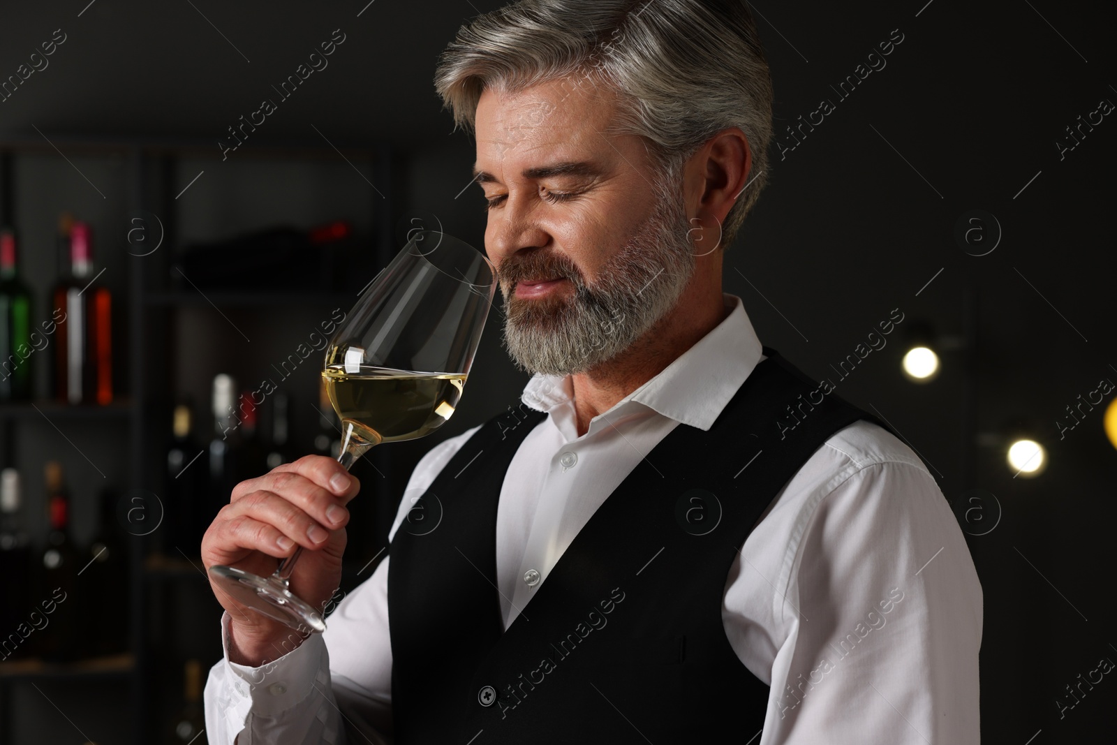 Photo of Professional sommelier tasting white wine in glass indoors