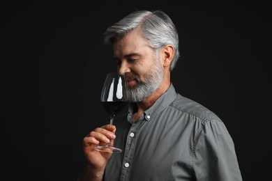 Photo of Professional sommelier tasting red wine on black background