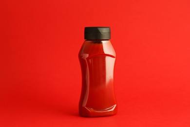 Photo of Ketchup in plastic bottle on red background