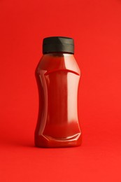 Photo of Ketchup in plastic bottle on red background