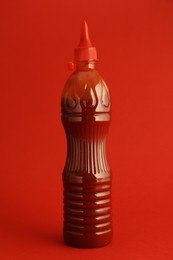 Photo of Ketchup in plastic bottle on red background