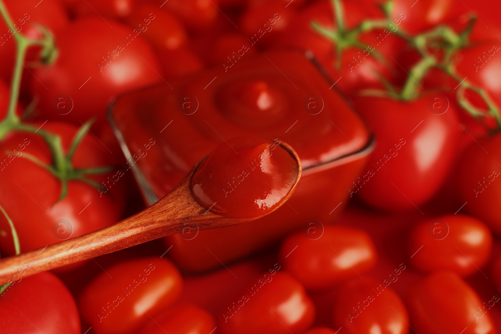 Photo of Spoon with delicious ketchup over tomatoes, closeup