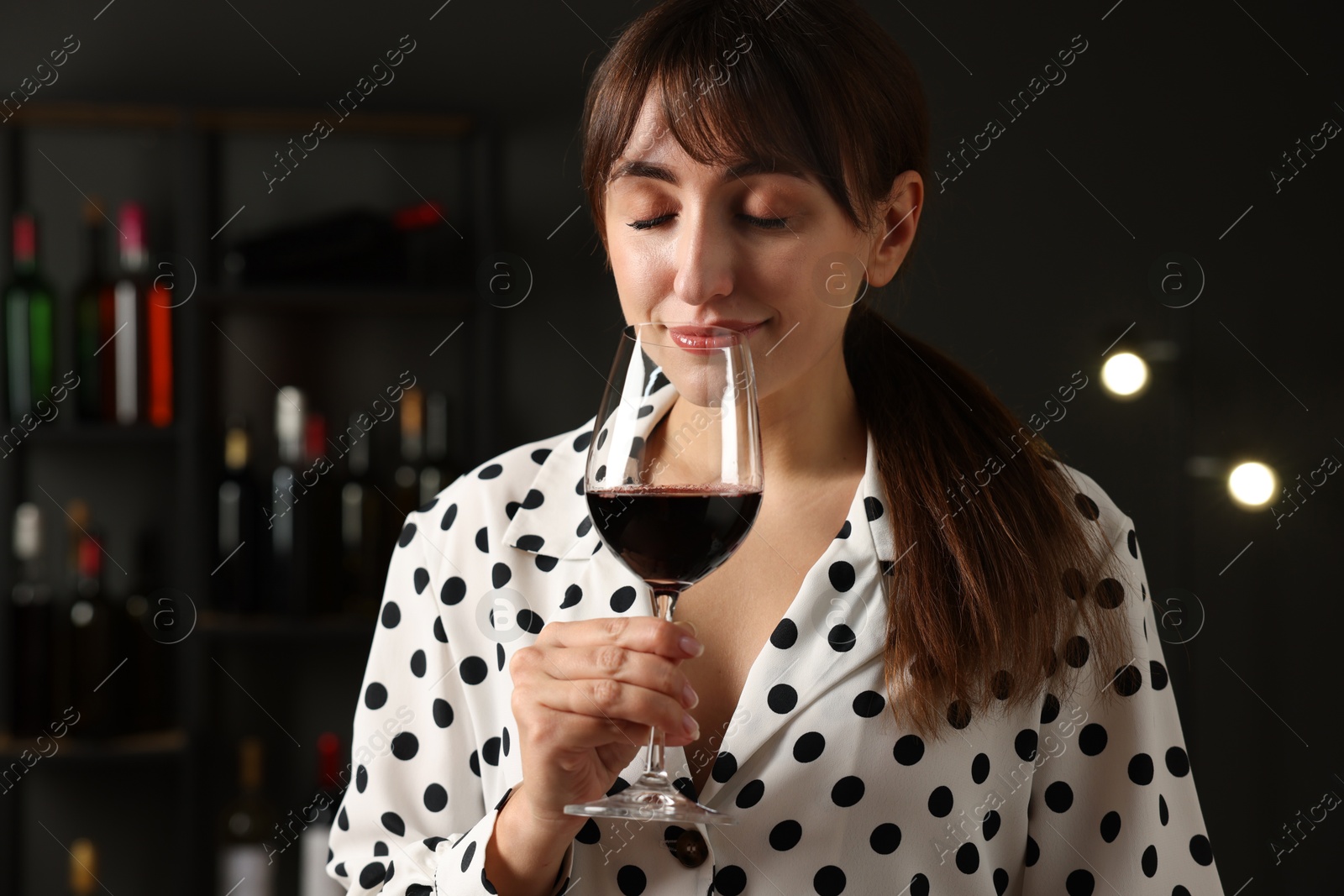 Photo of Professional sommelier tasting red wine in glass indoors