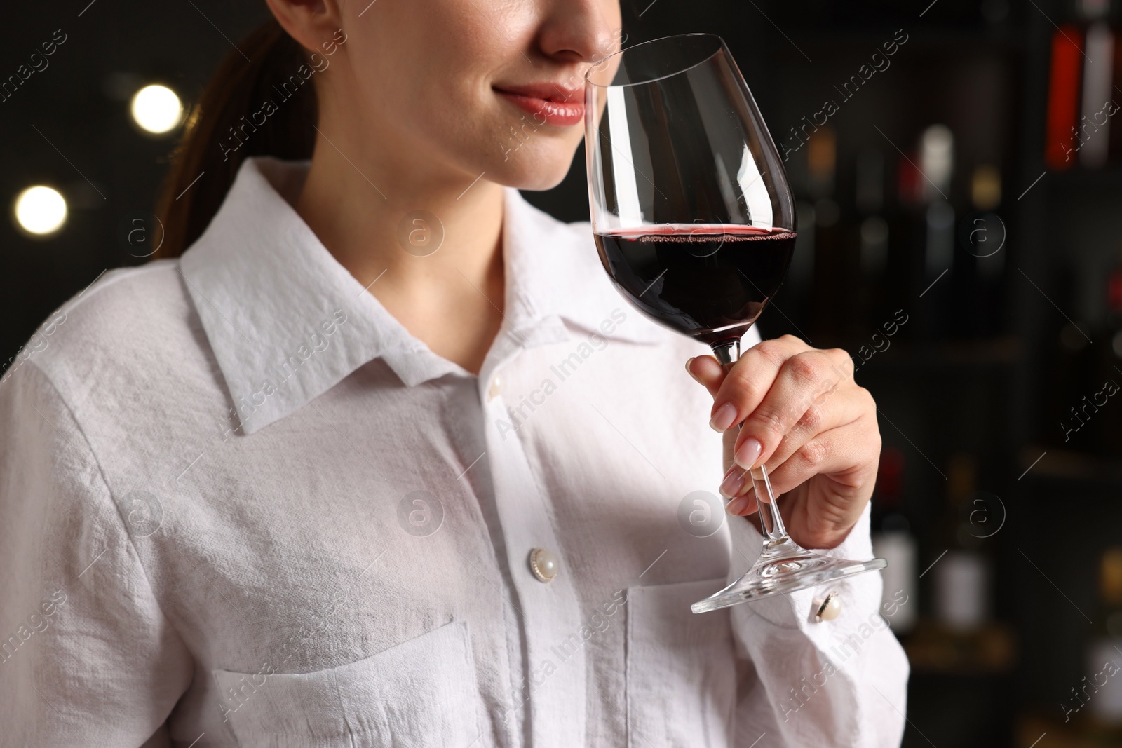 Photo of Professional sommelier tasting red wine in glass indoors, closeup