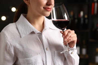 Photo of Professional sommelier tasting red wine in glass indoors, closeup