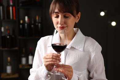 Photo of Professional sommelier tasting red wine in glass indoors